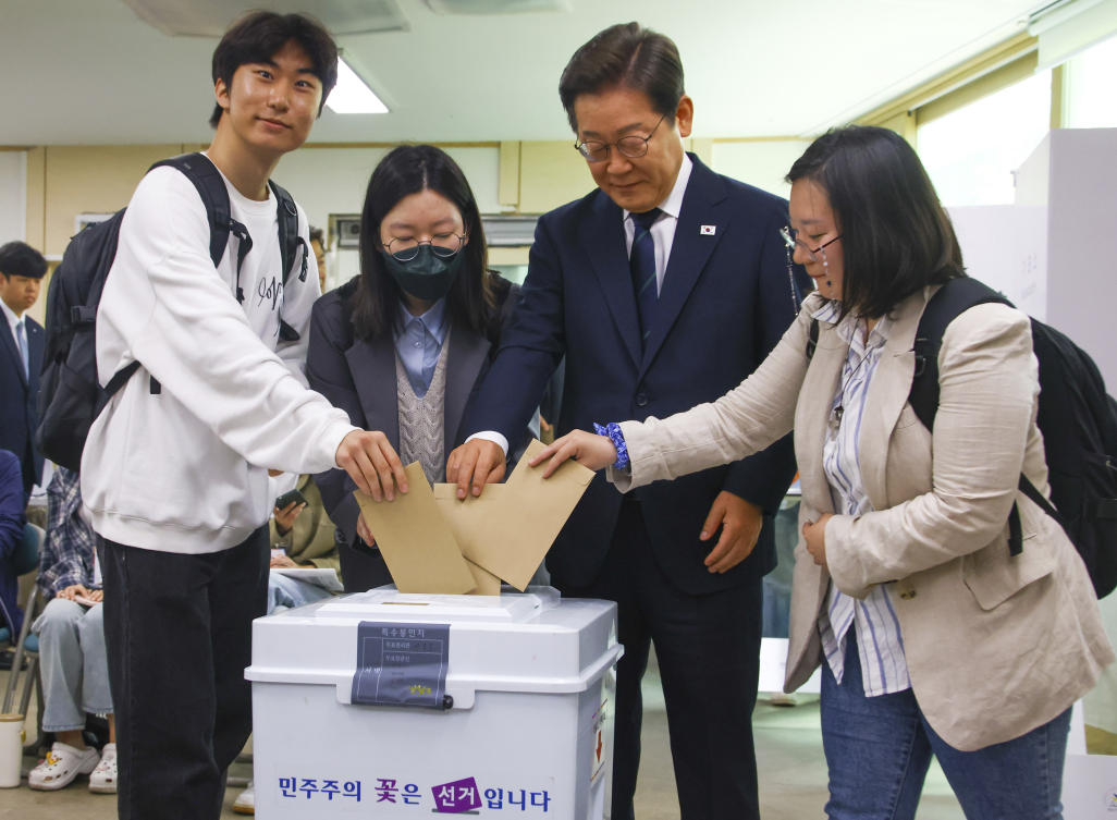 South Korean Democratic Party’s presidential candidate Lee Jae-myung, second from right, and young people cast their early votes for the June 3 presidential election at a polling station in Seoul on May 29, 2025. (Yonhap via AP)