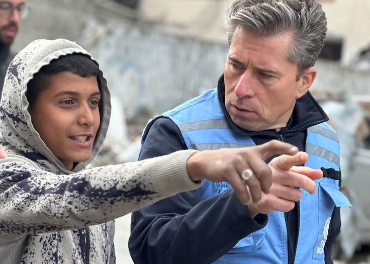UN relief chief Tom Fletcher talks to a young boy in northern Gaza during the ceasefire in February. (UNOCHA/Olga Cherevko)