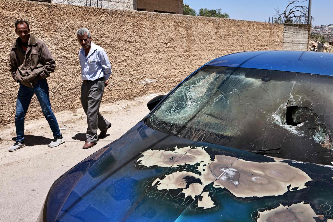 Palestinian men walk past a burned car reportedly set on fire during an attack by Israeli settlers in Rammun village, northeast of Ramallah in the occupied West Bank, on May 28, 2025. (AFP)