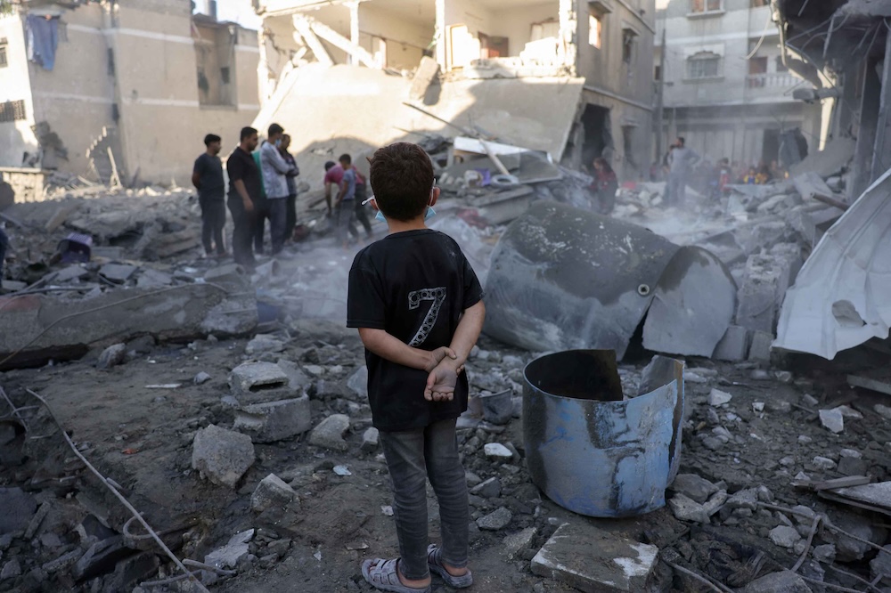 A boy watches as Palestinians check the site of an overnight Israeli strike in Jabalia in the central Gaza Strip, on May 30, 2025. (AFP)