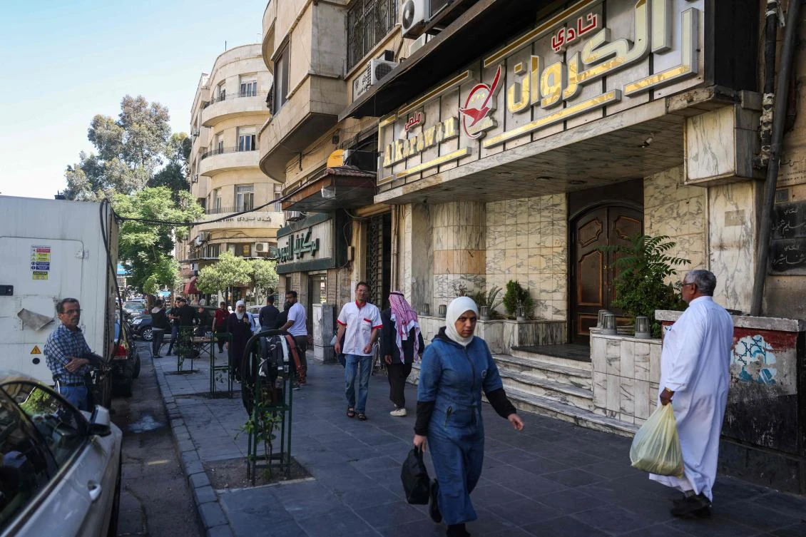 People walk past the closed entrance of Al-Karawan nightclub, which was attacked by gunmen overnight, on Damascus’ Saadallah Al-Jabri street on May 5, 2025. (AFP)