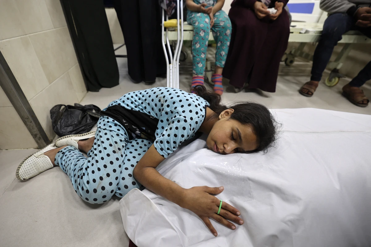 A Palestinian girl mourns over the shrouded body of her mother, killed in an Israeli strike, ahead of her funeral at Al-Awda Hospital at the Nuseirat refugee camp in the central Gaza Strip, May 7, 2025. (AFP)