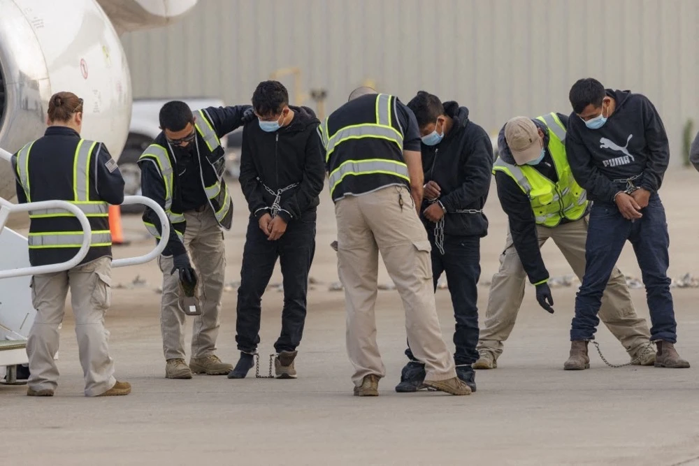 Security personnel pat down shackled migrants detained by ICE. (Getty Images/AFP)