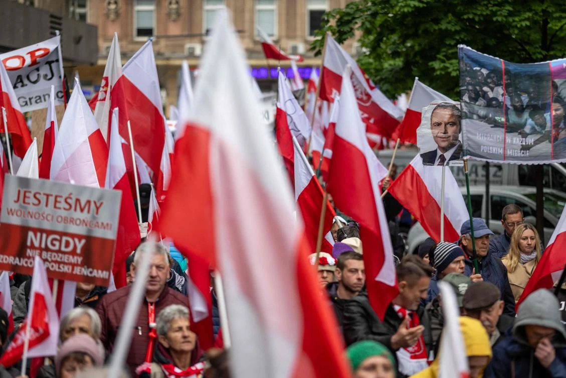 A picture of Karol Nawrocki, candidate for the 2025 Polish presidential election supported by Poland’s right-wing Law and Justice (PiS) party, is seen among polish national flags as right wing supporters take part in an anti-migration protest in Warsaw on May 10, 2025. (AFP)