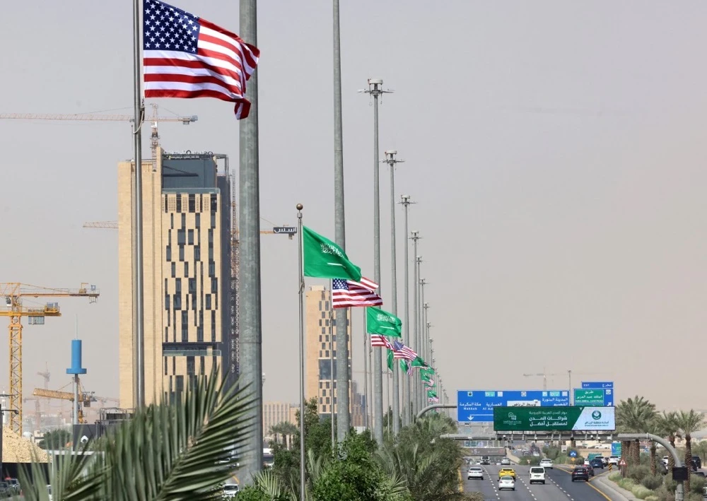 Traffic flows past Saudi and US flags on a main road in Riyadh on May 12, 2025, hours before of a visit by US President Donald Trump to Saudi Arabia. (AFP)