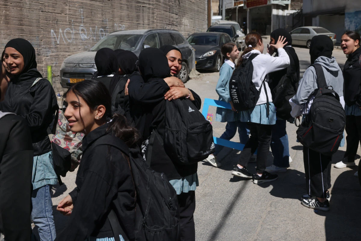 Palestinian schoolgirls embrace as they leave a school run by the UNWRA in the Shoafat refugee camp in east Jerusalem on May 8, 2025, as Israeli security forces reportedly prepare to close the school. (AFP)
