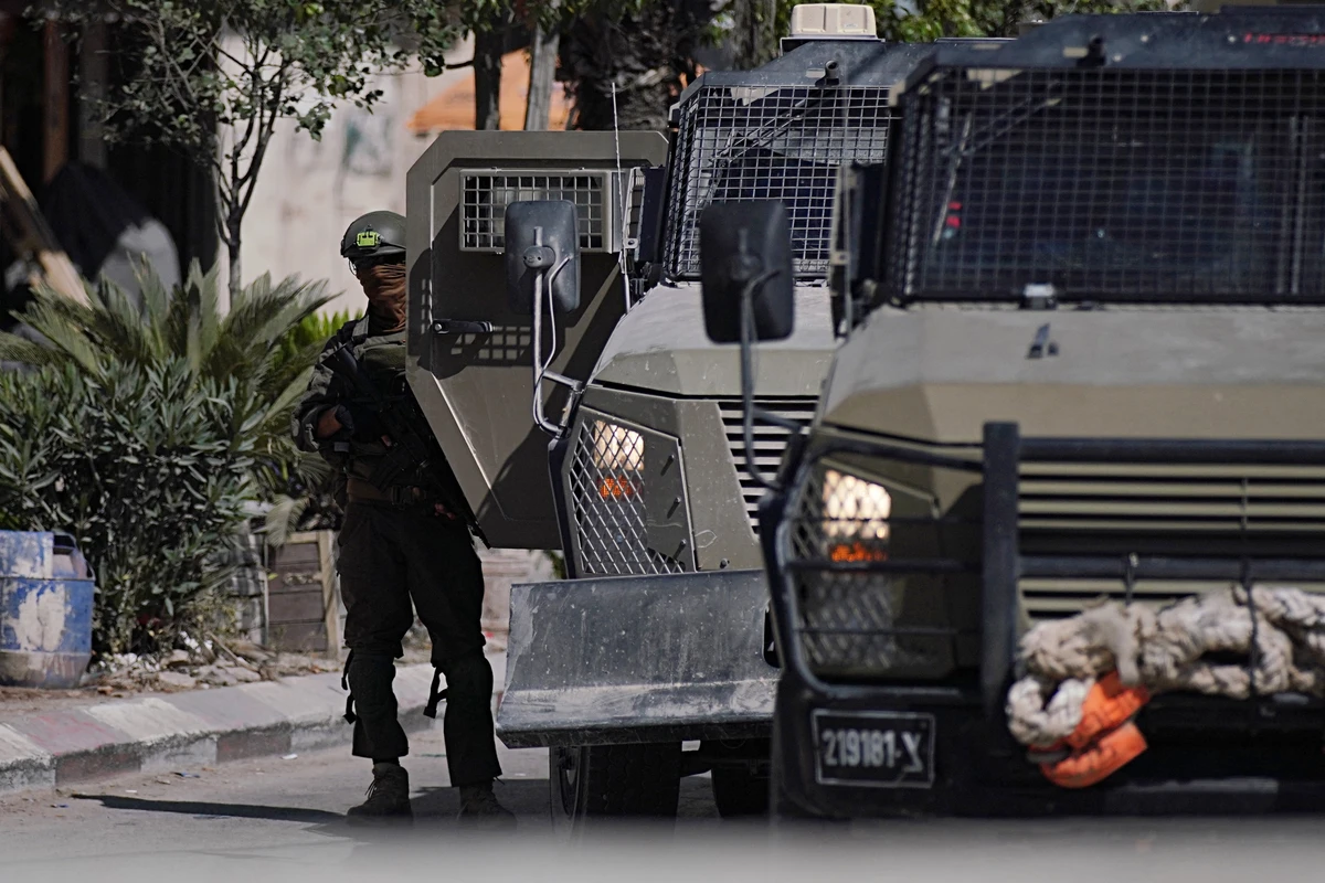 An Israeli soldier stands next to military vehicles while conducting a raid in the Palestinian city of Jenin in the occupied West Bank, May 21, 2025. (AFP)