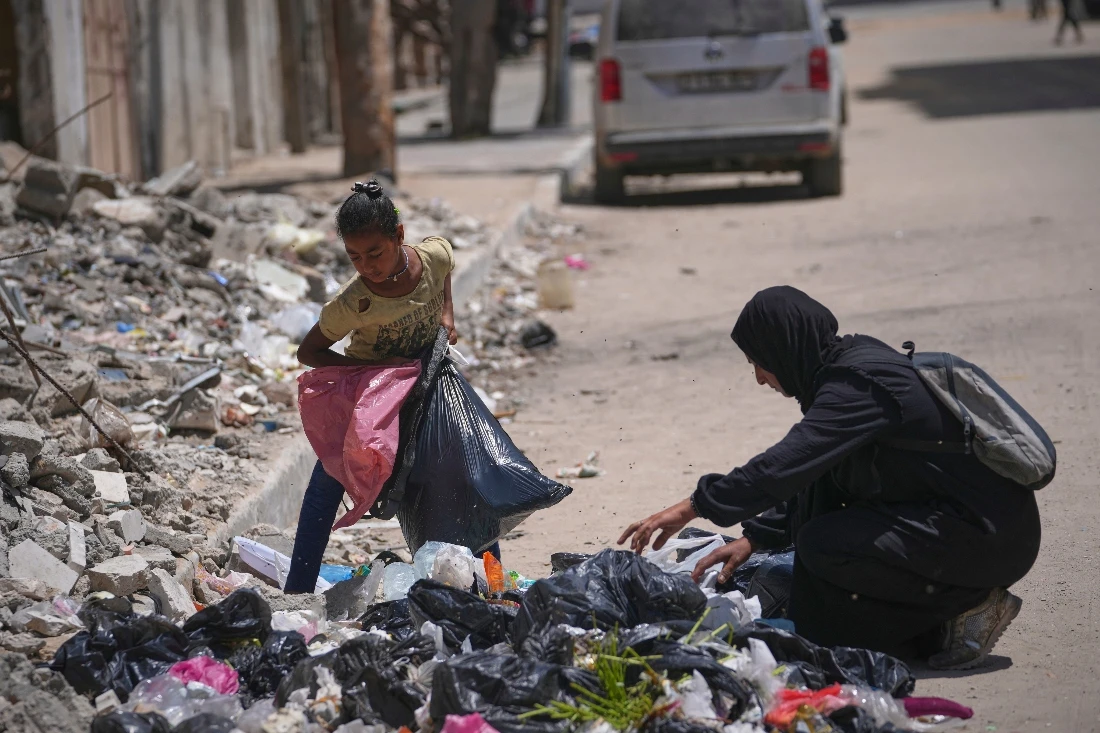 Mother Islam Abu Taiema with her 9 year old daughter rummage for food in a pile of garbage in Gaza. (AP)