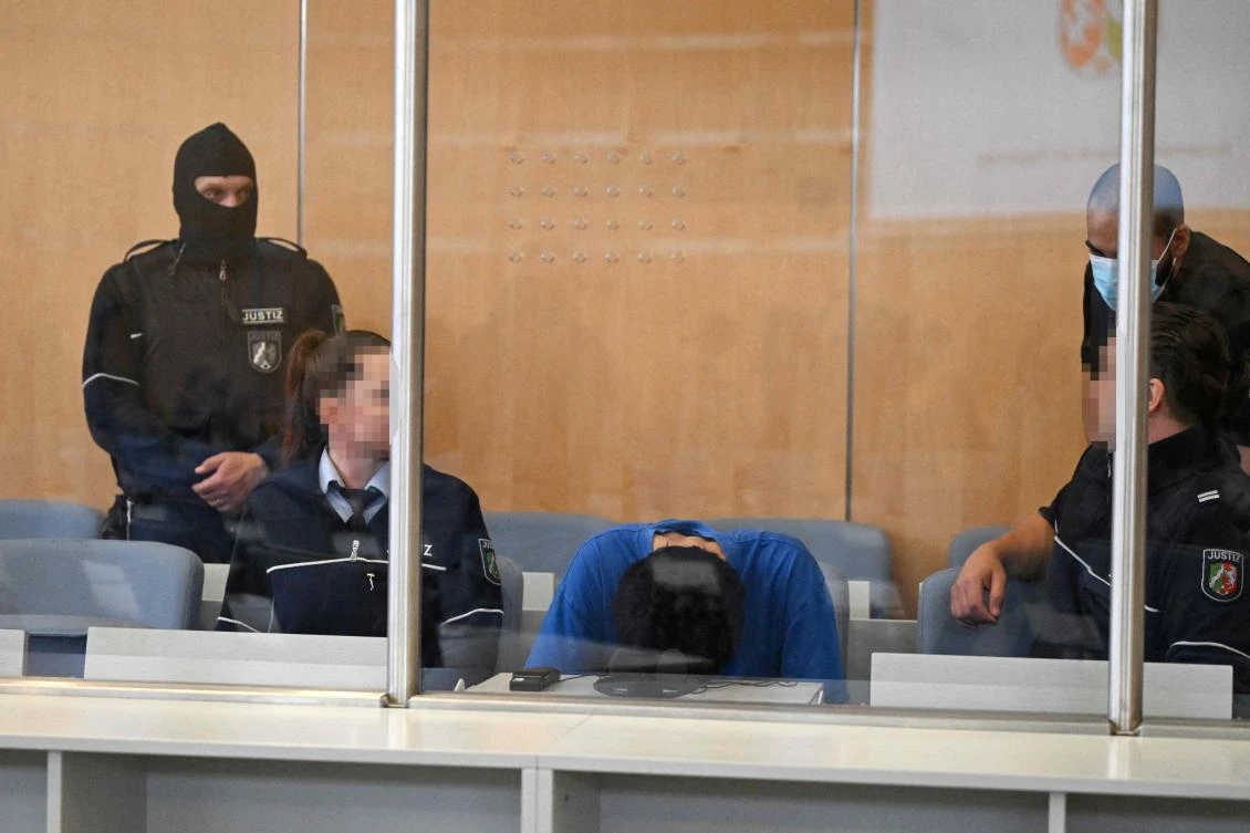 Syrian defendant Issa Al H. bends over as he sits next to judicial officers in the dock in the courtroom in Duesseldorf, western Germany, on May 27, 2025, at the start of his trial over a deadly knife attack that killed three people in August 2024 in Solingen, western Germany, during a summer city festival. (AFP)