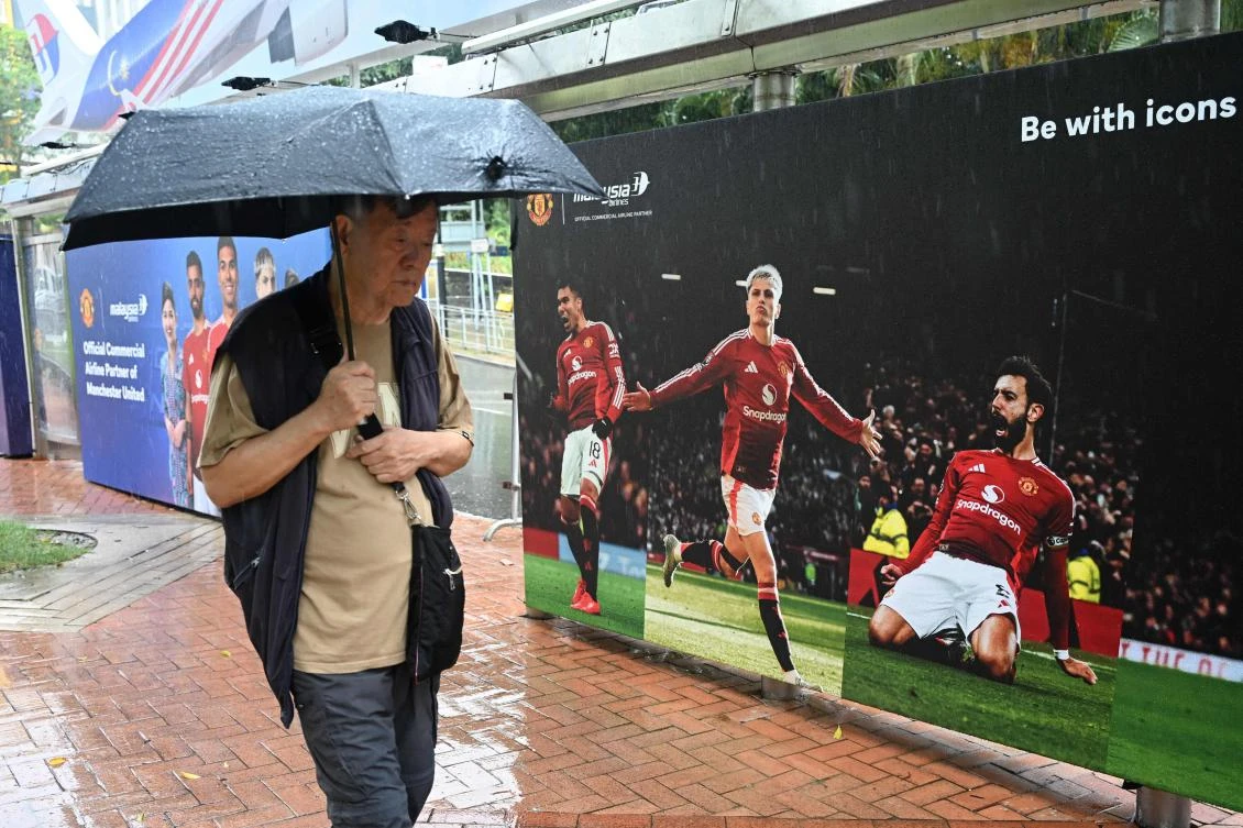 A man walks past posters of Manchester United players outside the Hong Kong Stadium on May 29, 2025 where they will play a Hong Kong team. (AFP)