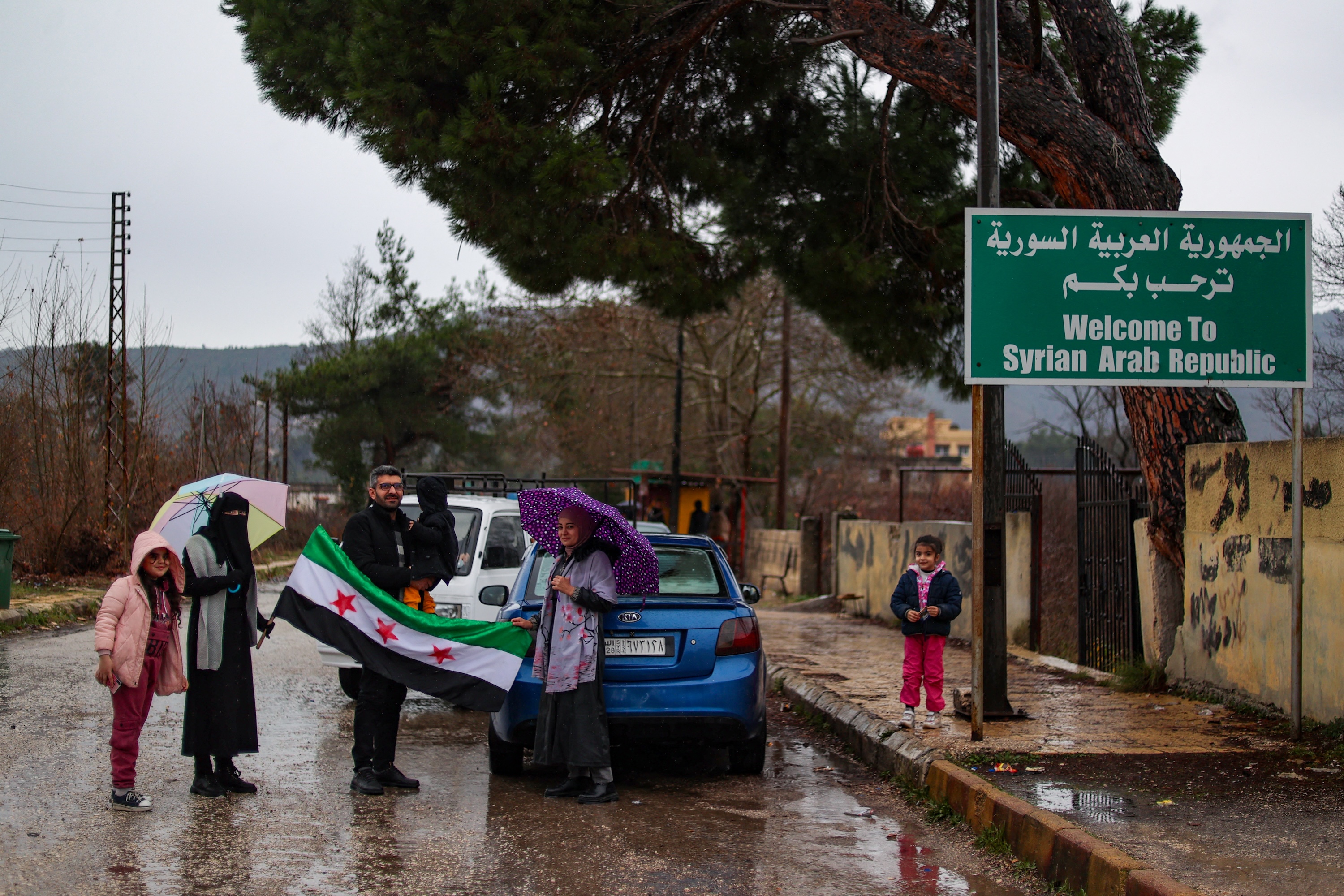People display an independence-era Syrian flag as after crossing over into Syria from Turkey through the Kassab crossing, Dec. 27, 2024. (AFP)