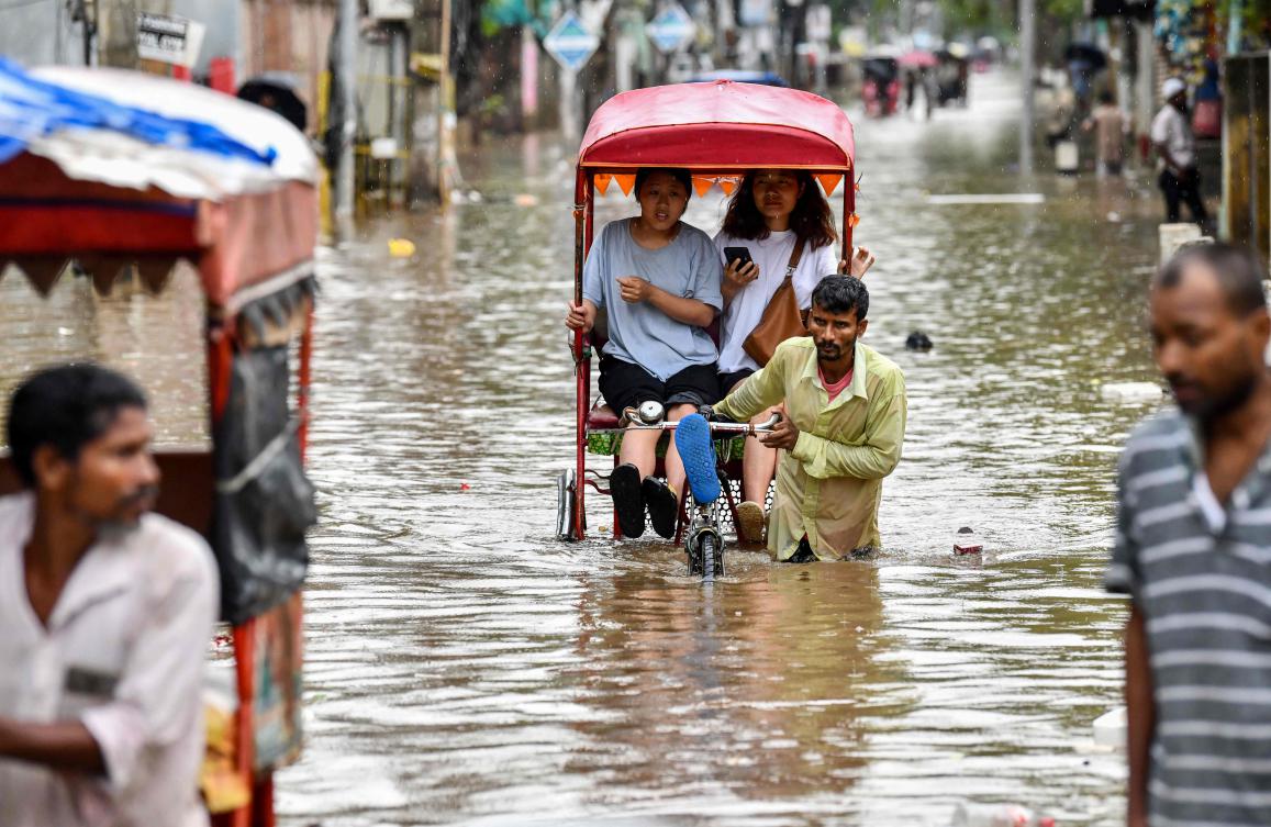 Women commute in cycle rickshaws through a flooded street after heavy rains in Guwahati, in India's Assam state on May 31, 2025. (AFP)