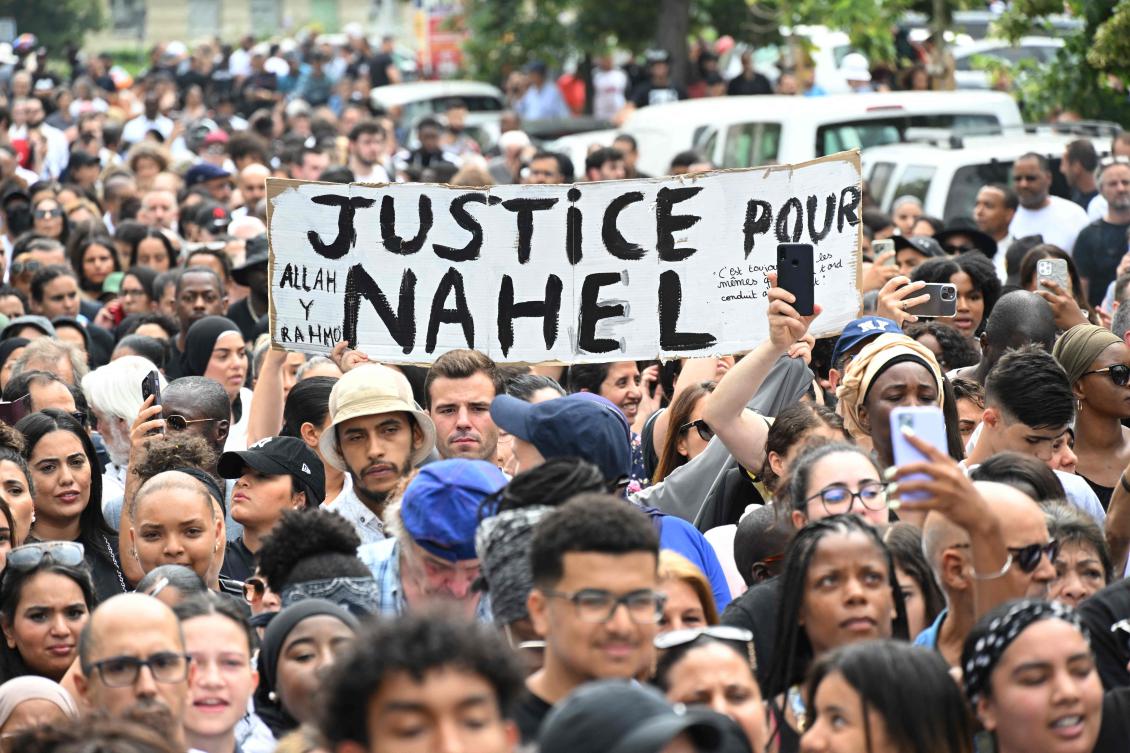 Attendees hold a banner reading “Justice for Nahel,” during a commemoration march for a teenage driver shot dead by a policeman, in the Pablo Picasso area of the Parisian suburb of Nanterre, on Jun. 29, 2023. (AFP)