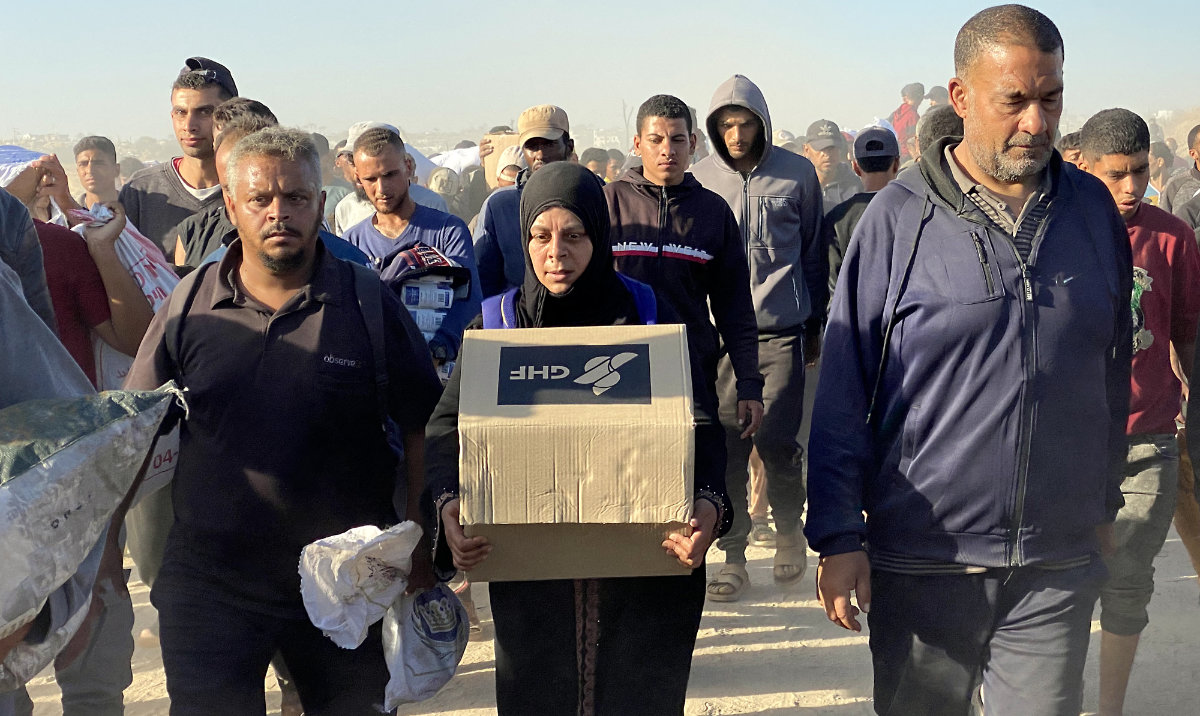 A woman carries a box of relief supplies from the Gaza Humanitarian Foundation (GHF), a private US-backed aid group, as displaced Palestinians return from aid distribution centers in Rafah to their tents in the southern Gaza Strip. (AFP)