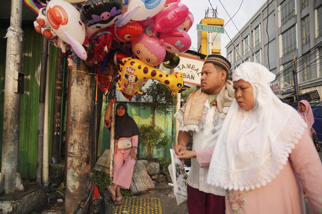 An inflatable toy vendor waits for customers as Muslims arrive to perform Eid Al-Adha prayer on a street in Jakarta, Indonesia on June 6, 2025. (AP)