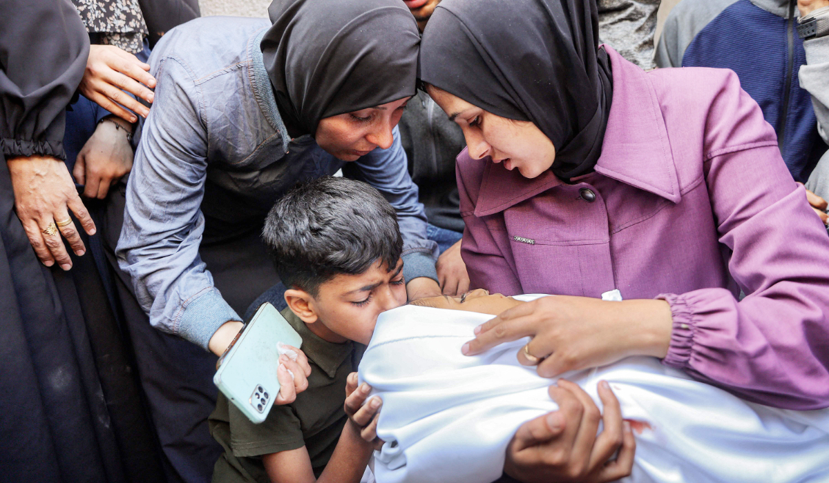 A Palestinian boy kisses the body of a victim who was killed during Israeli bombardment at Al-Shifa Hospital in the besieged Gaza Strip. (AFP)