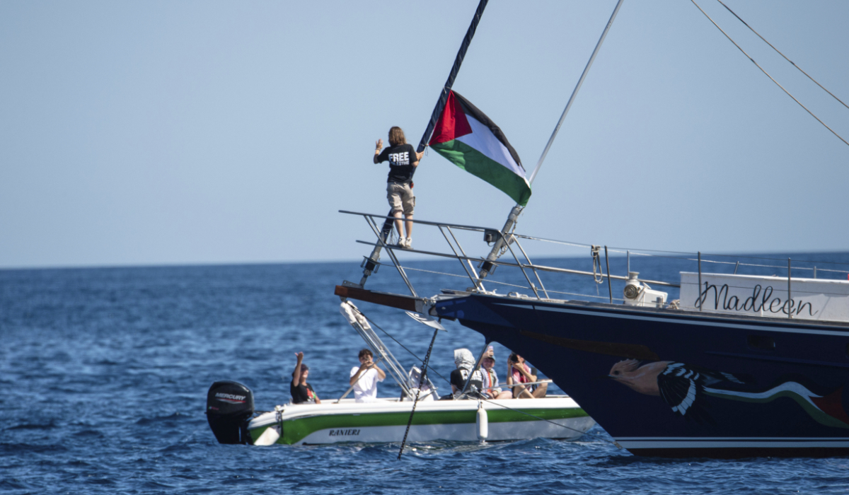 Climate activist Greta Thunberg stands near a Palestinian flag after boarding the Madleen boat and before setting sail for Gaza along with activists of the Freedom Flotilla Coalition, departing from the Sicilian port of Catania, Italy, Sunday, June 1, 2025. (AP)