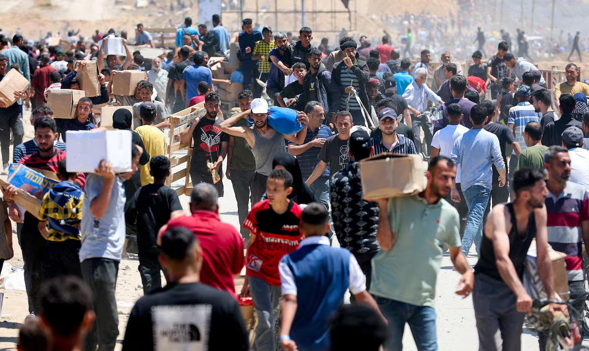 Palestinians carry aid supplies which they received from the US-backed Gaza Humanitarian Foundation, in the central Gaza Strip. (Reuters/File)