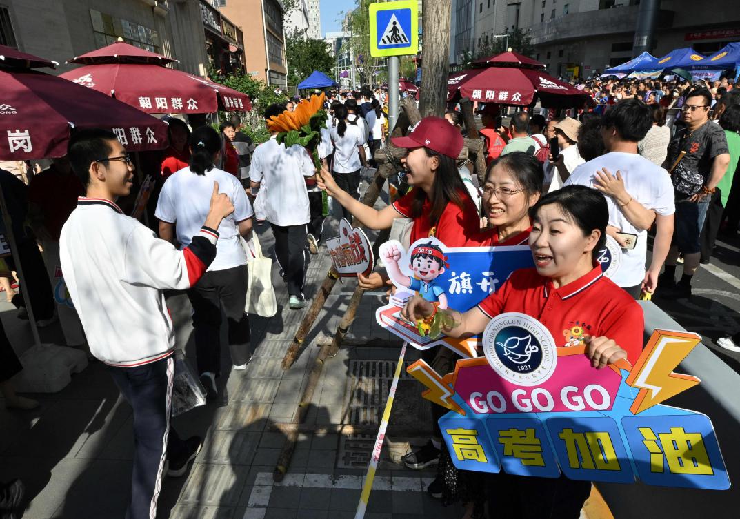 School staff members welcome students as they enter a school during China’s National College Entrance Examination, known as “gaokao”, outside a high school in Beijing on June 7, 2025. (AFP)