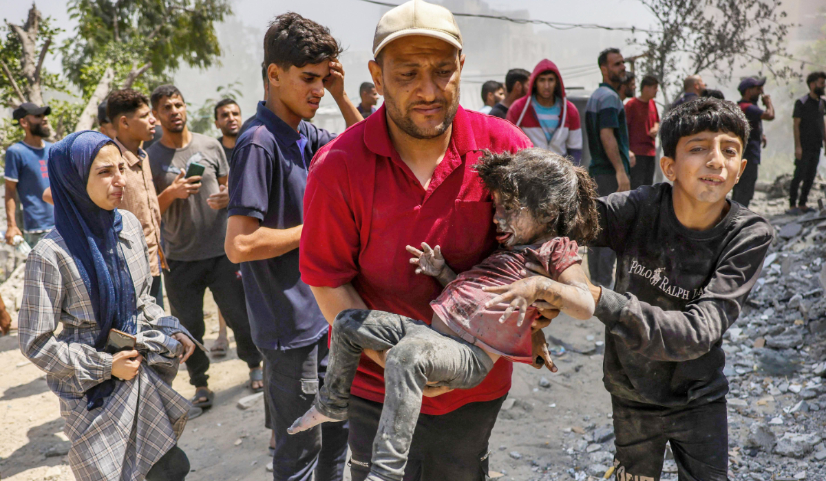 A Palestinian man carries a child pulled from the rubble of the Shaheen family home that was targetted in an Israeli strike in the Saftawi neighbourhood, west of Jabalia, in the northern Gaza Strip on June 9, 2025. (AFP)