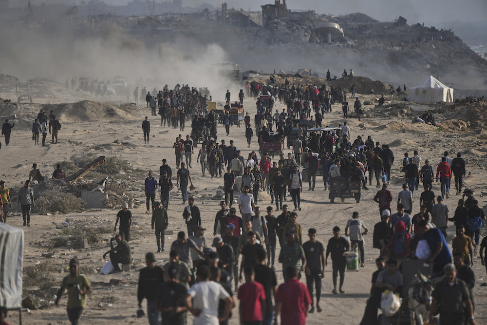 Displaced Palestinians walk past the ruins of destroyed buildings along the Gaza City shoreline on Monday, June 9, 2025. (AP)