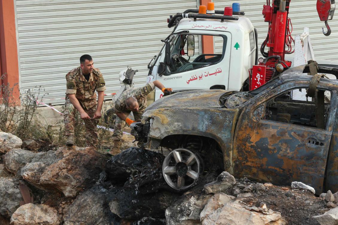 Army officers inspect the carcass of a car that was targeted in a reported Israeli drone attack in the southern Lebanese town of Al-Numairiyah on June 9, 2025. (AFP)