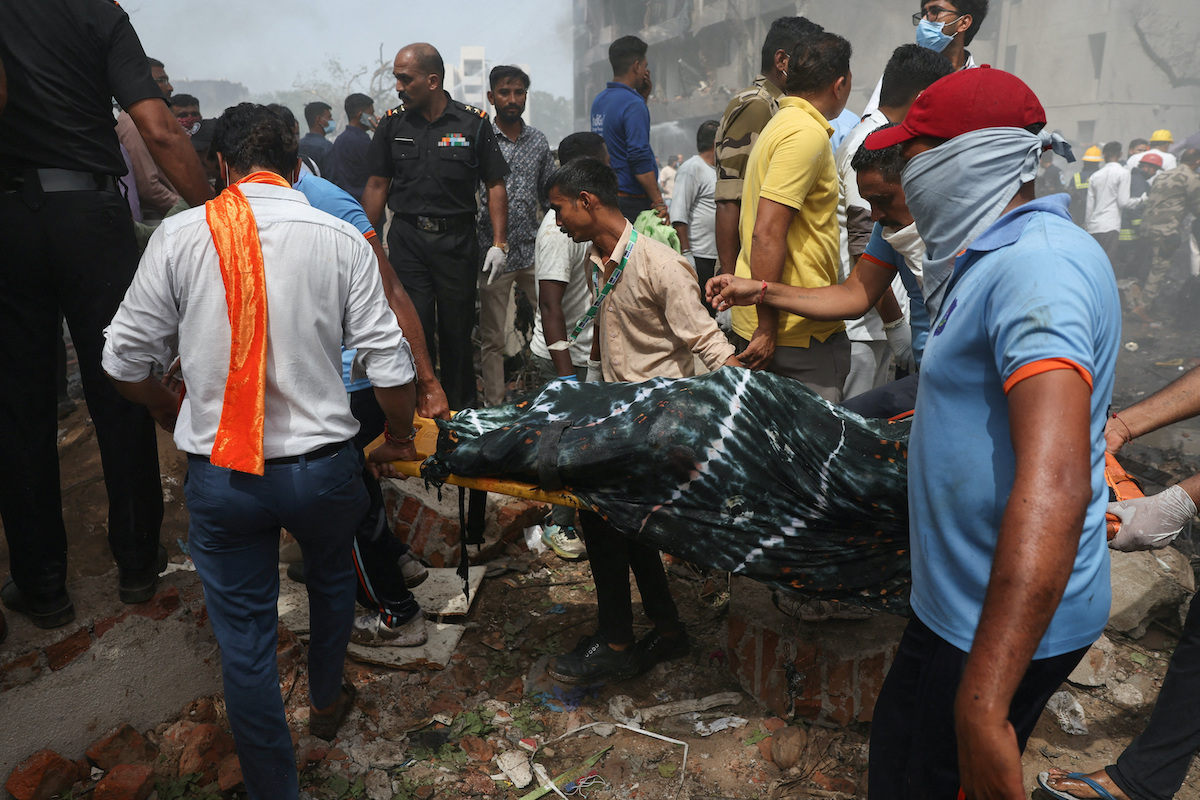 The body of a victim is carried from the crash site after an Air India Boeing 787 Dreamliner plane crashed in Ahmedabad, India on Thursday. (Reuters)