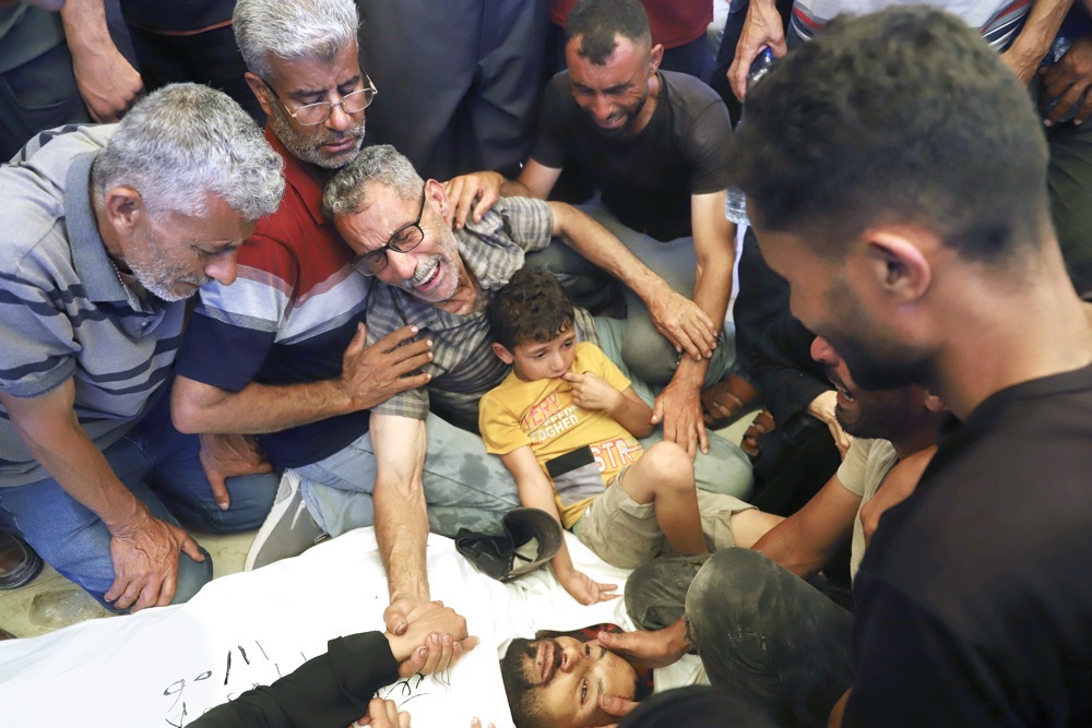 A Palestinian mourns over the body of his son, who was killed while heading to an aid distribution hub, during his funeral in Rafah, southern Gaza Strip. (AP)