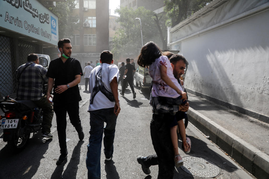 People run along a street amid smoke following the Israeli strikes on Iran, in Tehran, Iran, June 15, 2025. (Reuters)