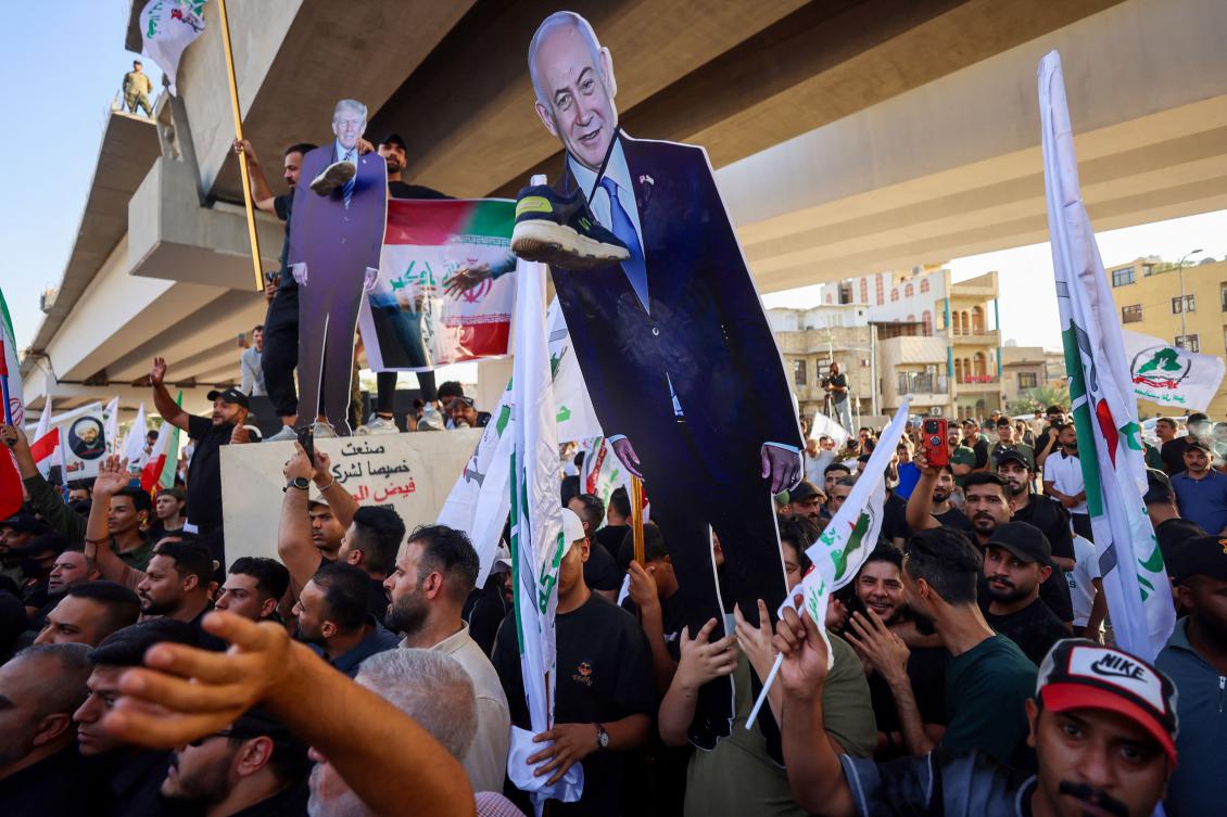 Supporters of Iraqi pro-Iran groups hold a cutout of US President Donald Trump and Israeli Prime Minister Benjamin Netanyahu during a protest in support of Iran, in Baghdad near a bridge leading to the green zone, on Jun. 16, 2025. (AFP)