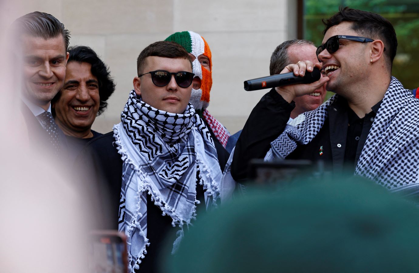 Irish rap group Kneecap singer, Liam O'Hanna (3L), who performs under the stage name Mo Chara, stands with band mates Naoise O Caireallain, aka Moglai Bap (R) and JJ O'Dochartaigh aka DJ Provai (C), outside Westminster Magistrates' Court in London on June 18, 2025, after O'Hanna was released on bail until his next hearing in August. (AFP)
