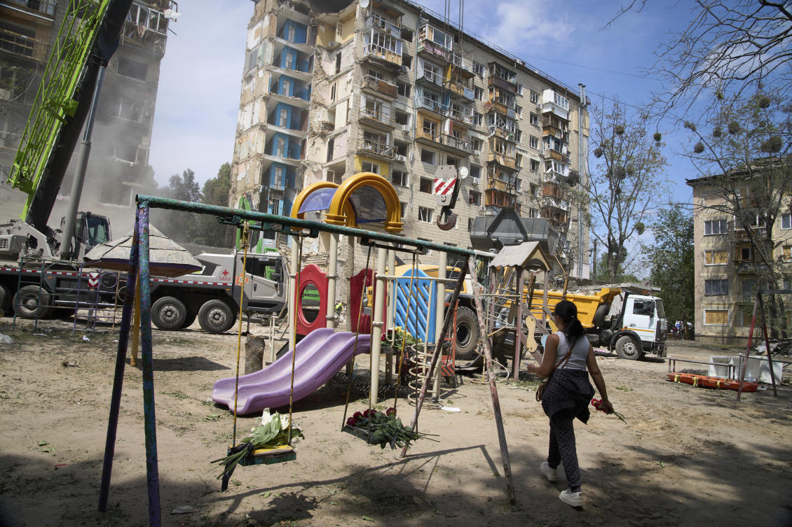 A woman lays flowers at the site of Russia’s Tuesday deadly missile attack that ruined a multistory residential building in Kyiv, Jun. 18, 2025. (AP)