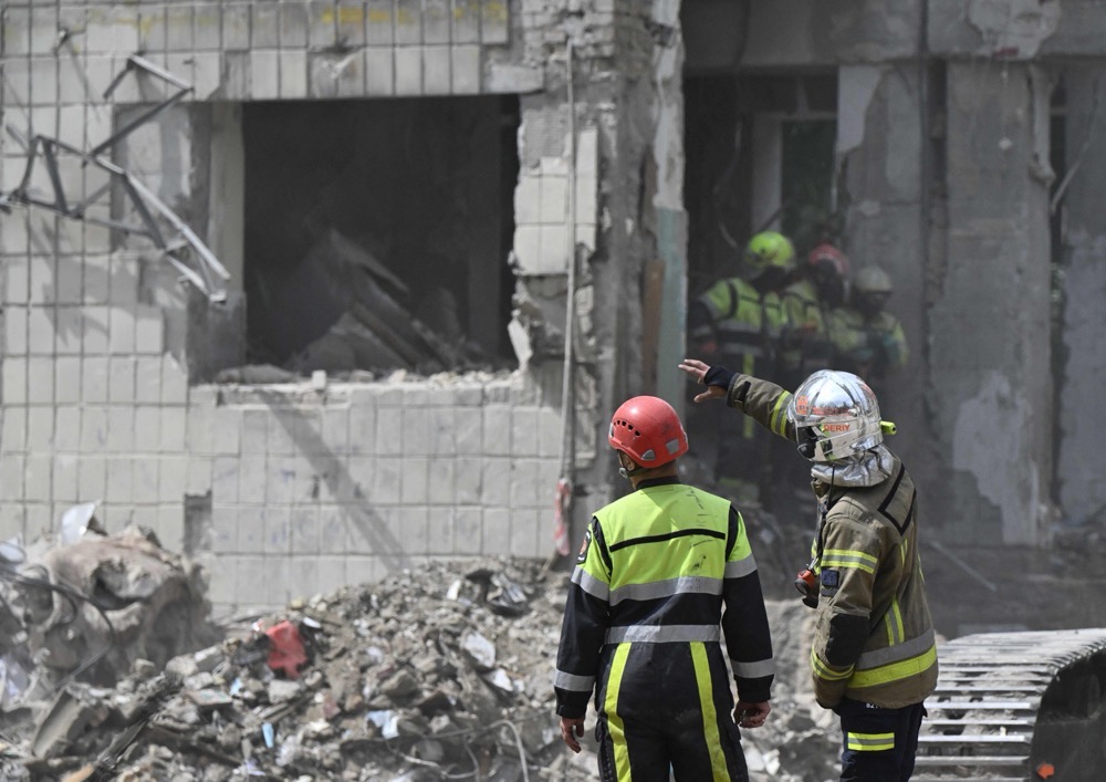 Ukrainian rescuers clear debris as they continue a search operation at the site of a residential building, heavily damaged following a Russian missile strike the previous day, in Kyiv on June 18, 2025. (AFP)