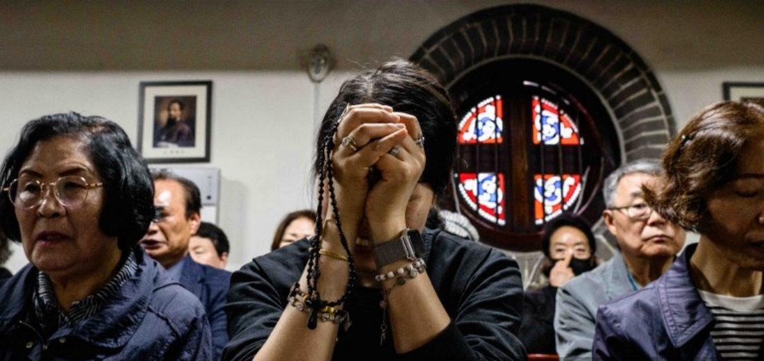 People pray as they pay their respects near a portrait of Pope Francis displayed inside Myeongdong Cathedral in Seoul, South Korea. (AFP)