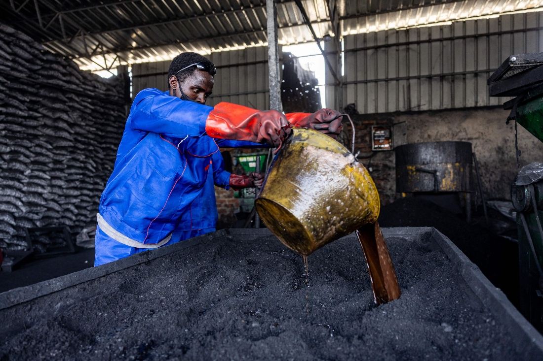 A worker pours a gum arabic-based binder at Grace International's green coal production site in N'Djamena, Chad. (AFP)