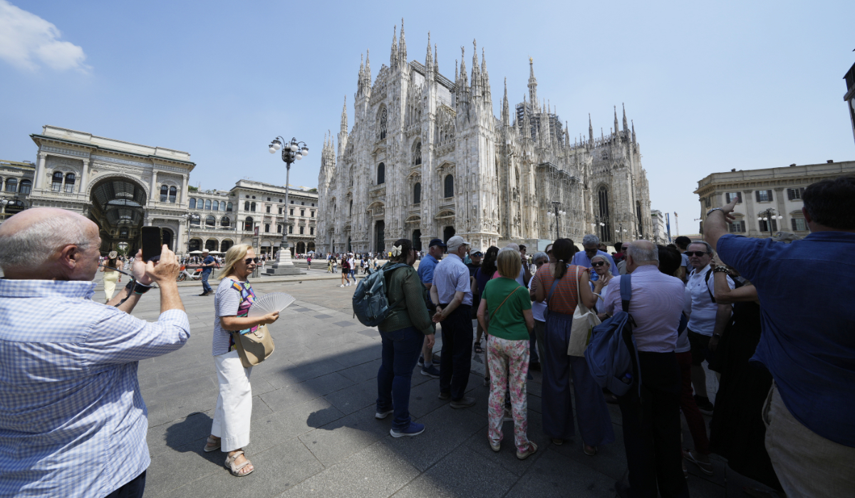 Tourist shelter from the hot sun in front of the Duomo gothic cathedral, in Milan, Friday, June 20, 2025. (AP)