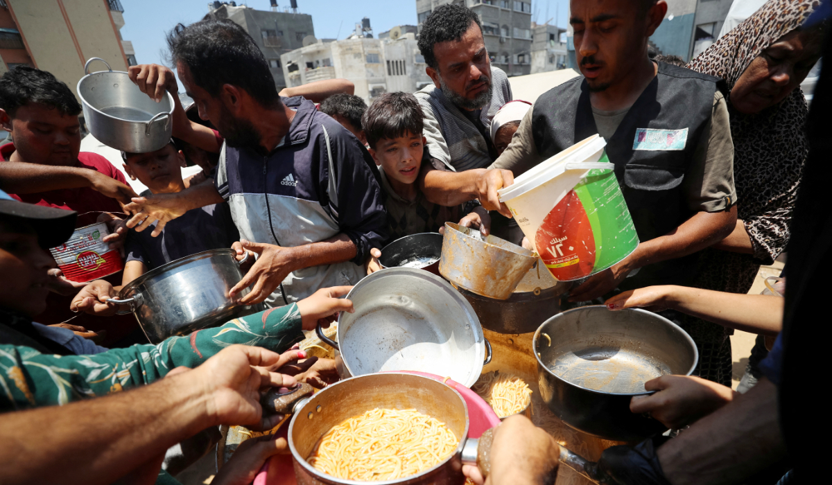 Palestinians wait to receive food cooked by a charity kitchen, in Gaza City, June 21, 2025. (REUTERS)
