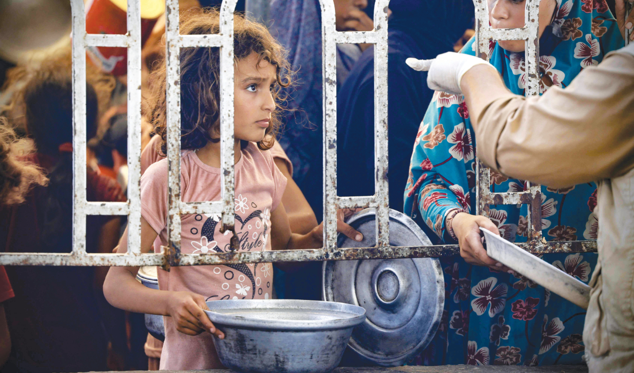 A Palestinian child waits in front of a hot meal distribution kitchen in Rafa’s Al-Mawasi area in the southern Gaza Strip on Sunday. (AFP)