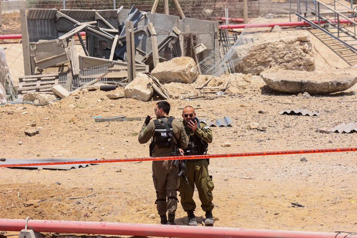 Members of Israeli security forces stand in a cordoned-off area at the impact site of an Iranian rocket near the southern city of Ashdod, June 23, 2025. (AFP)