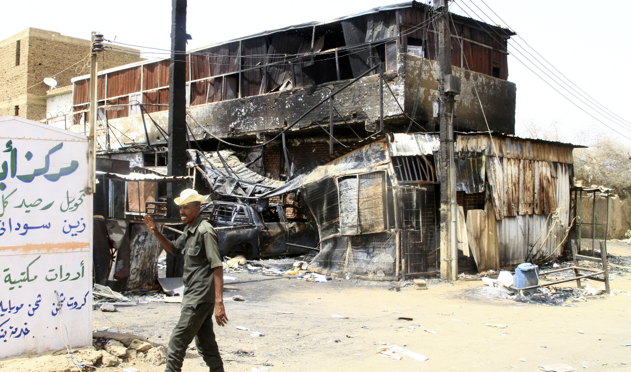 A Sudanese army soldier waves as he walks past a war-damaged building in Salha, south of Omdurman, two days after the Sudanese army recaptured it from the paramilitary Rapid Support Forces (RSF), on May 22, 2025. (AFP/File)