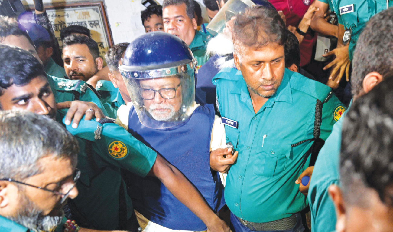 Police officers escort KM Nurul Huda, center, Bangladesh’s former chief election commissioner, to a court in Dhaka on Monday. (AFP)