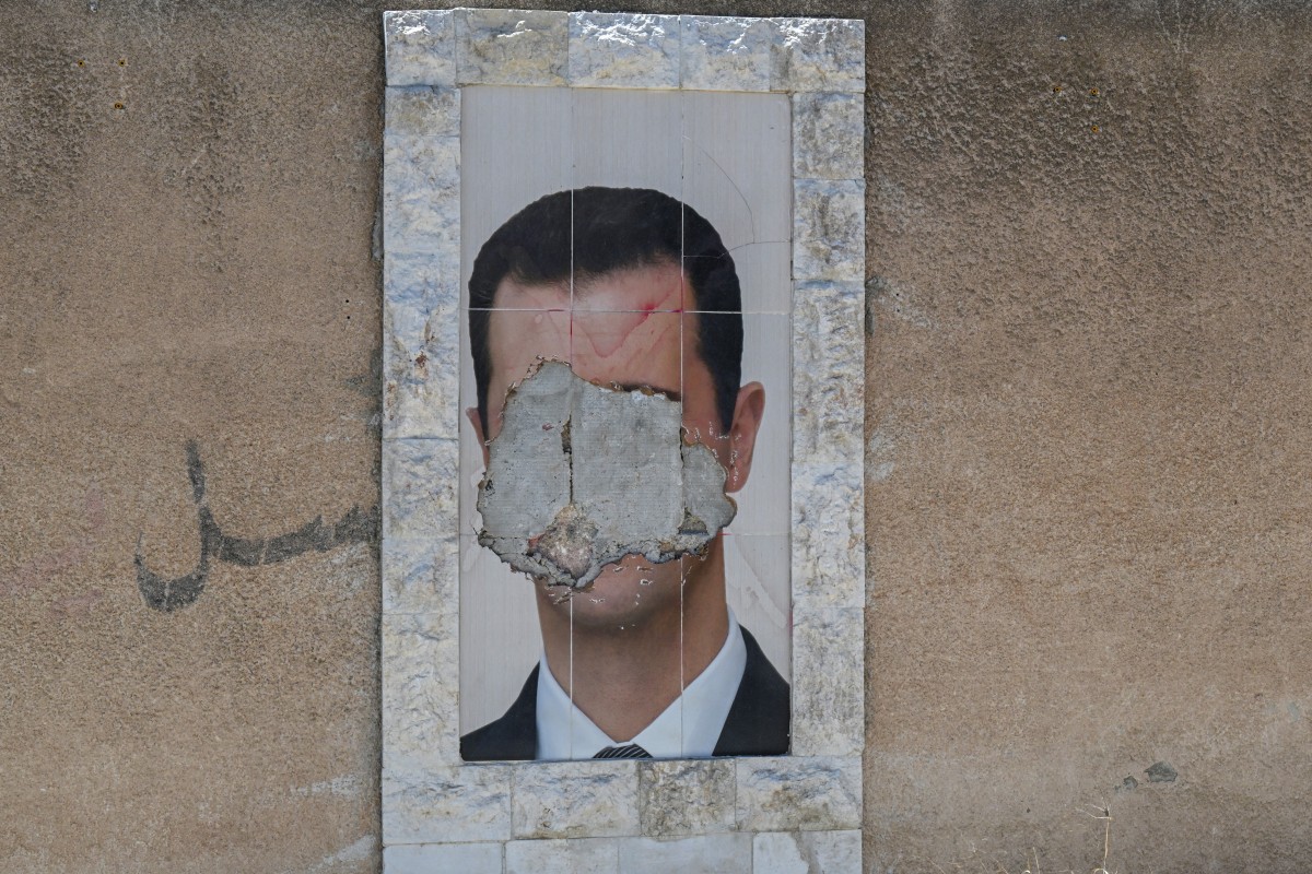 A defaced portrait of Syria's ousted president Bashar al-Assad hangs on a wall in the capital Damascus, June 2, 2025. (AFP)