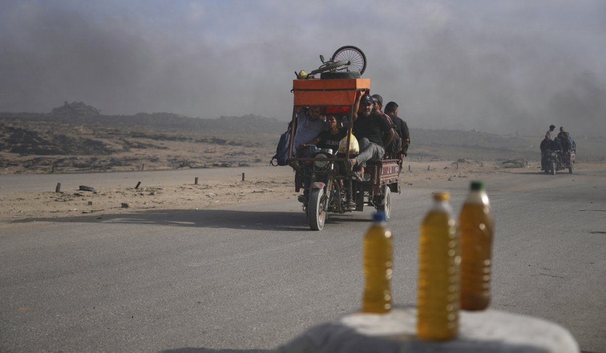 Residents ride through black smoke from makeshift burners used to extract fuel from melted plastic to sell along the Sea Road south of Gaza City, Sunday, June 22, 2025. (AP)