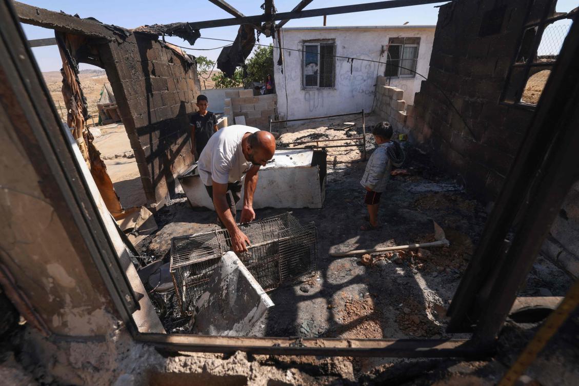 Palestinians Nasser Ishreiteh and his children clear burnt belongings in the living and kitchen area of their house after a reported attack overnight by Israelis from a nearby settlement south of Hebron city in the occupied West Bank on June 25, 2025. (AFP)
