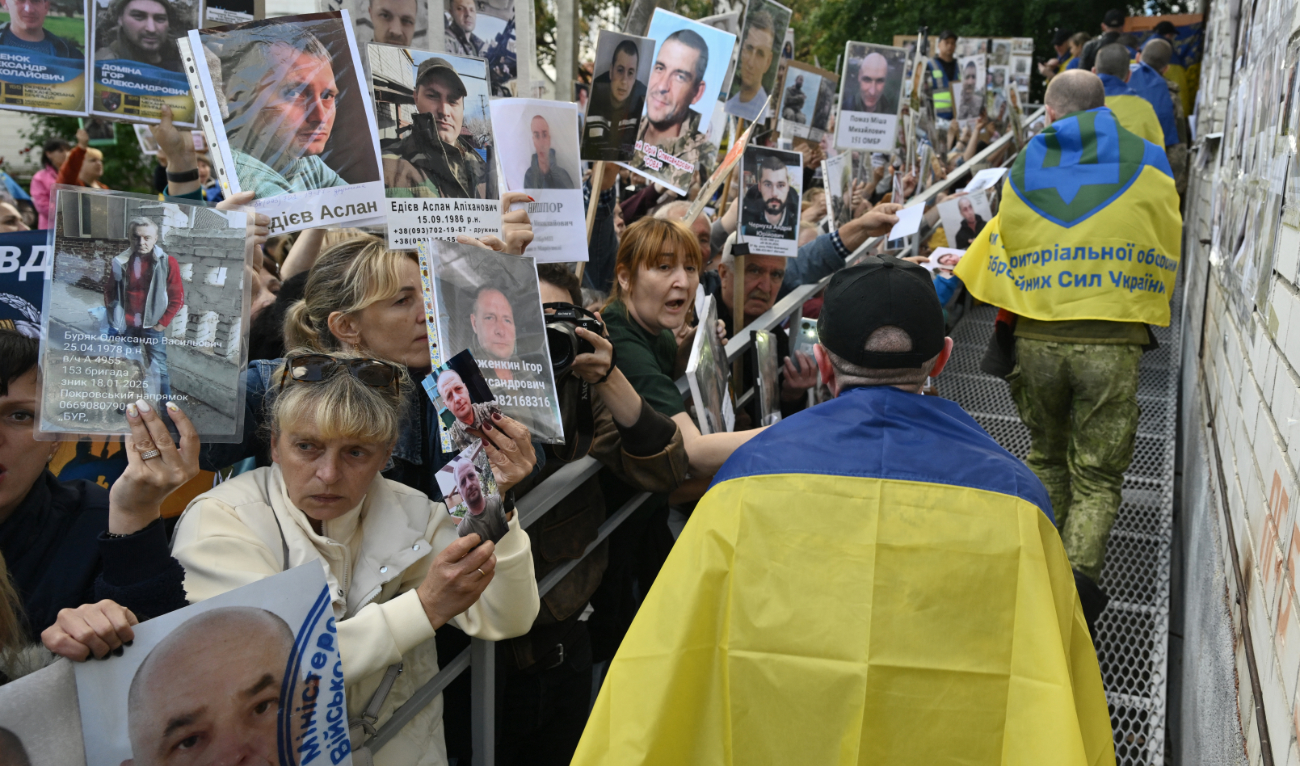 Released Ukrainian prisoners of war (POW) wrapped in a Ukrainian national flag walk past crowds holding portraits of their missing or captured relatives and friends, upon their arrival after a prisoner exchange in the Chernigiv region on June 26, 2025. (AFP)