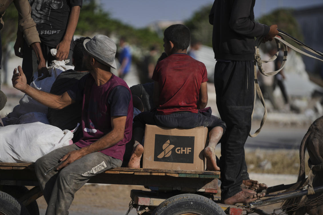Palestinians carry humanitarian aid packages near the Gaza Humanitarian Foundation distribution center in Khan Younis. (AP)