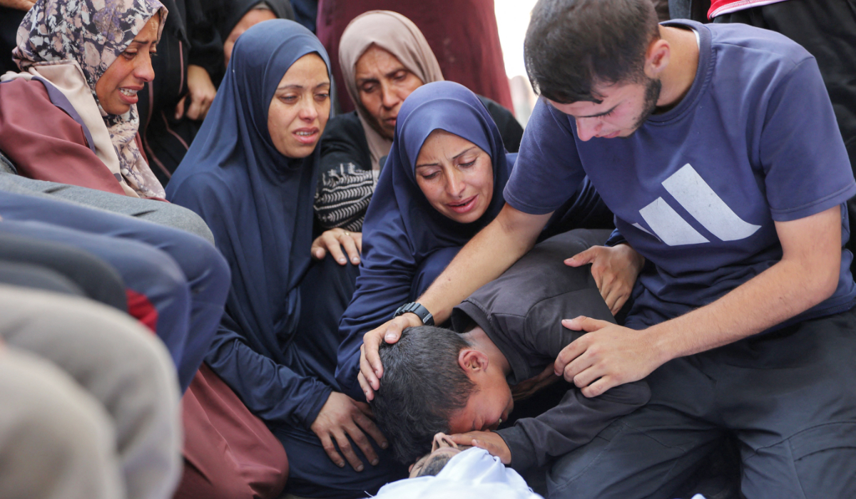 Palestinians on Saturday mourn over the bodies of loved ones killed during Israeli strikes, on the grounds of Al-Shifa Hospital in the central Gaza Strip. (AFP)