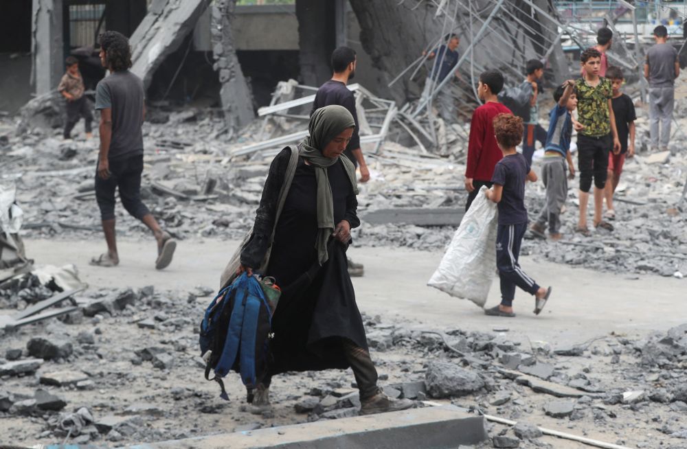 A Palestinian woman walks at the damaged site of an UNRWA school sheltering displaced people that was hit in an Israeli air strike on Sunday, in Gaza City, June 30, 2025. (Reuters)