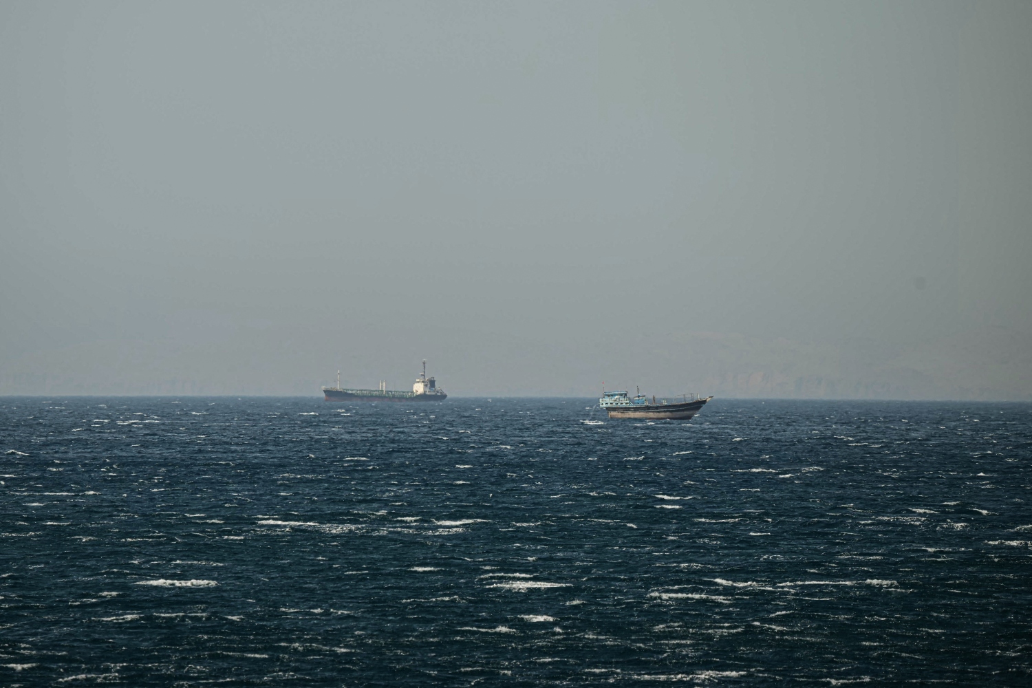 A ship and a Dhow sail in the Strait of Hormuz off the coast of Khasab, Oman. June 24, 2025 (File/AFP)