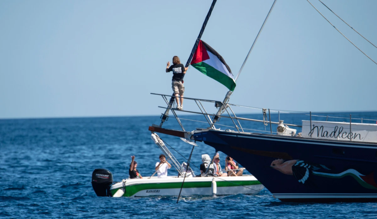 Climate activist Greta Thunberg stands near a Palestinian flag after boarding the Madleen boat and before setting sail for Gaza along with activists of the Freedom Flotilla Coalition, departing from the Sicilian port of Catania, Italy, Sunday, June 1, 2025. (AP)